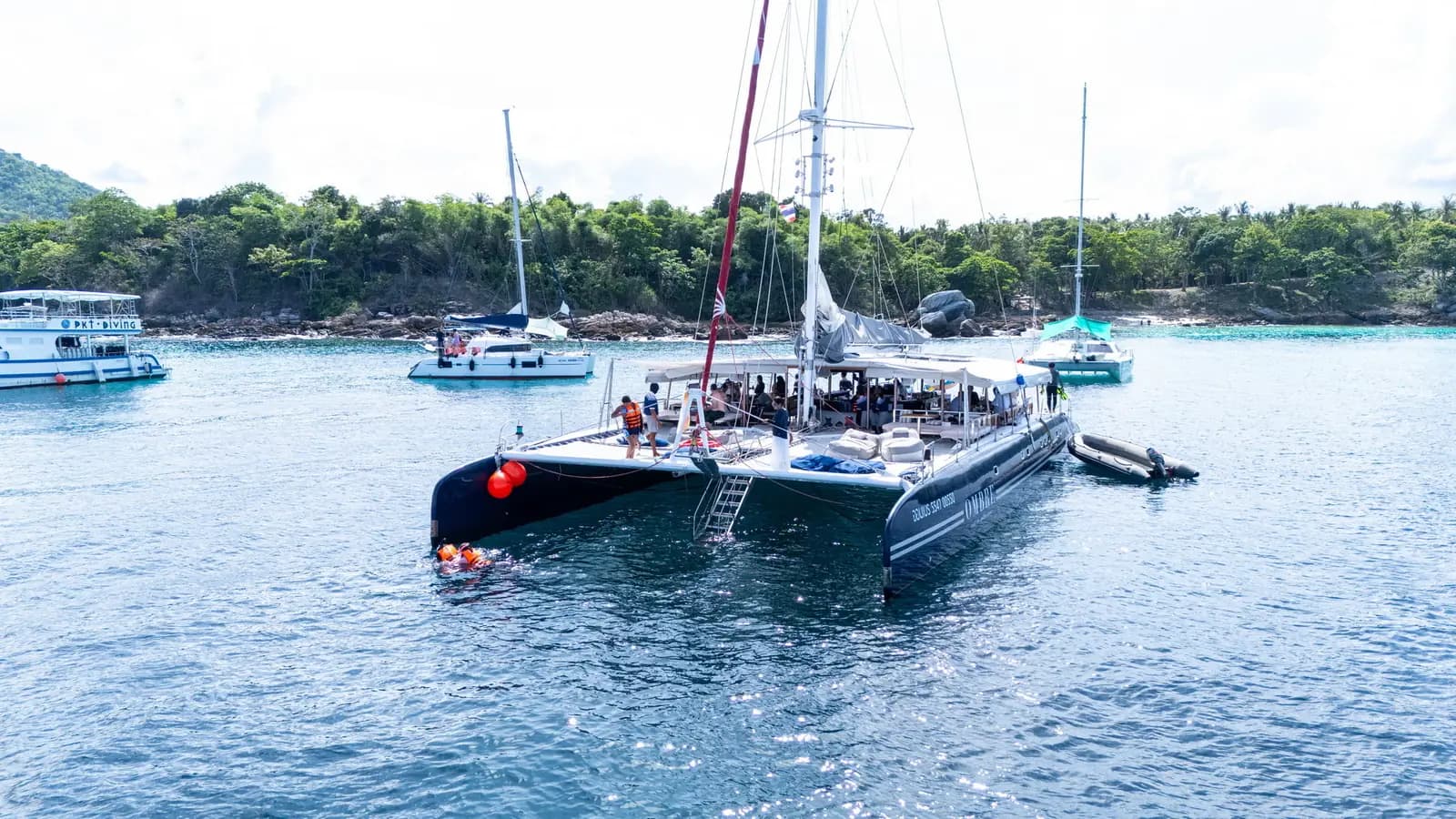OMBRE catamaran anchored in a sheltered bay near a green coastline