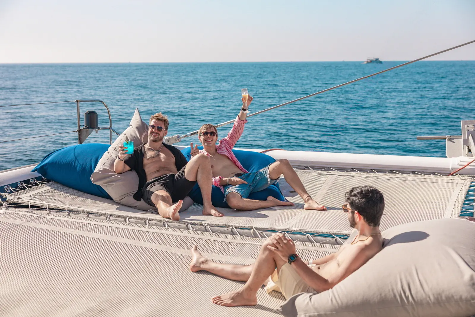 Guests reclining on blue and white beanbags across the catamaran bow