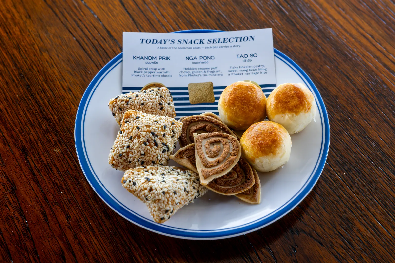 A plate of sandwiches and small pastries served on a wooden table