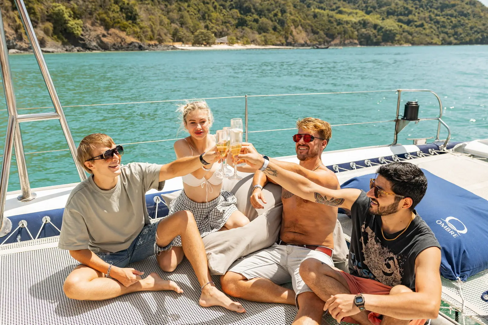 Four guests sitting together on the catamaran bow with drinks